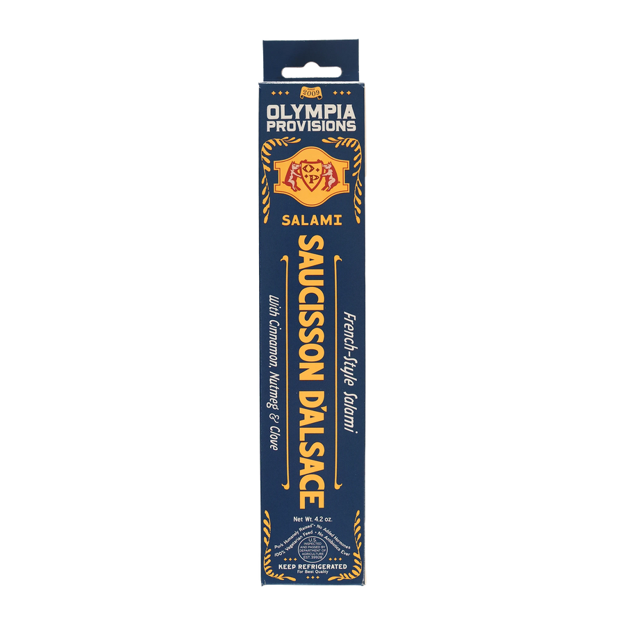 Olympia Provisions Saucisson d'Alsace with cinnamon, nutmeg, and clove, packaged in a blue box.