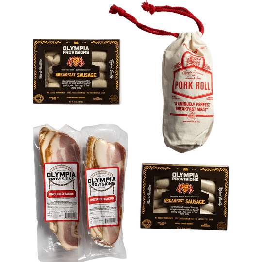 Two Olympia Provisions sausages in black packaging, two packages of sliced uncured bacon, and one pork roll in a canvas bag.