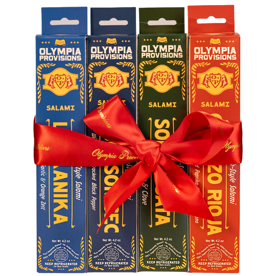 Four boxes of Olympia Provisions European-inspired Salami, wrapped in a large red ribbon bow.