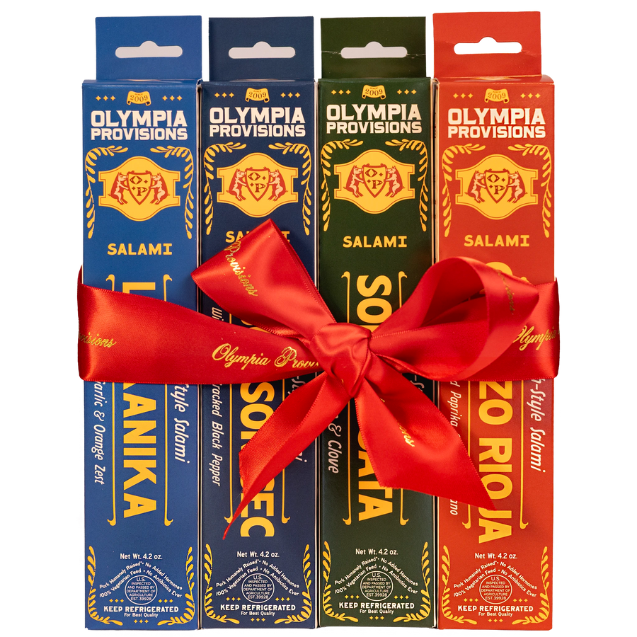 Four boxes of Olympia Provisions European-inspired Salami, wrapped in a large red ribbon bow.