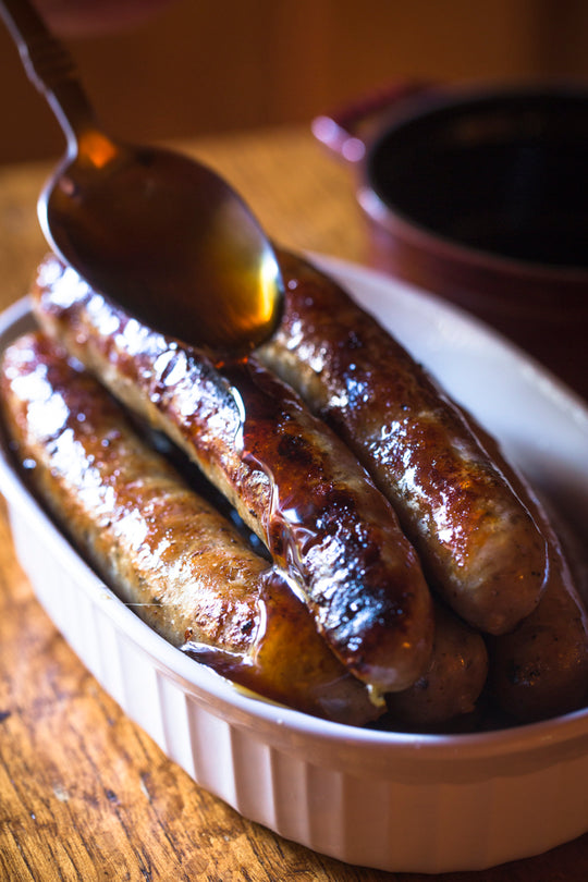 brekfast sausages in a dish being glazed in honey